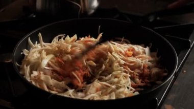 Fry cabbage with carrots in a pan. Cooking stewed cabbage. An unrecognizable person moves the ingredients in a frying pan. Close-up.