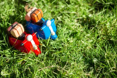 The concept of traveling on mopeds in spring or summer. Toy figures of mopeds on green grass in the sun.