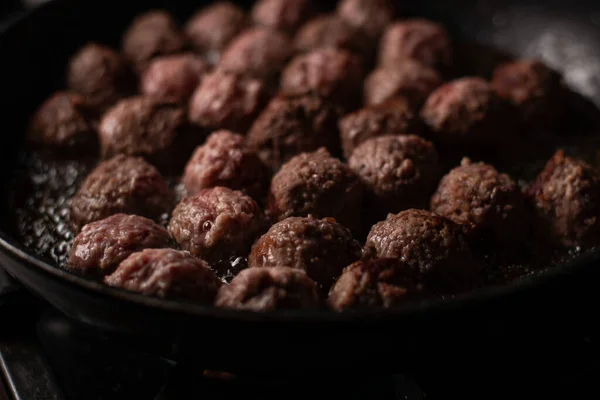 Meatballs in a frying pan. Making meatballs. Dark background.