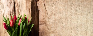 Ahşap arka planda bir buket lale. Hediye, bahar konsepti. Anneler Günü selamları. Pankart. Metin için yer