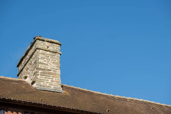 石煙突と屋根の一部は青い澄んだ空に対して古い家のタイルで作られた — ストック写真