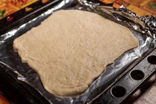 生面团在烘烤板上铺开 派或披萨的基地 家里的面团不均衡 — 图库照片