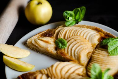 Nane yapraklarıyla süslenmiş elmalı Fransız turtası. İnce dilimlenmiş elma şekerli turtayı aç..