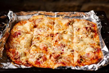 Pişirme tepsisinde ev yapımı pizza. Peynirli pizza, domates, pastırmalı ekmek..