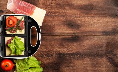 Farklı dolgularla sandviç pişirmek. Sandviç makinesi ve ahşap arka planda çeşitli malzemeler. Mesaj için yer. Pankart.