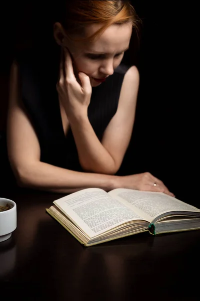Una Mujer Está Leyendo Libro Oscuridad Sienta Junto Mesa — Foto de Stock