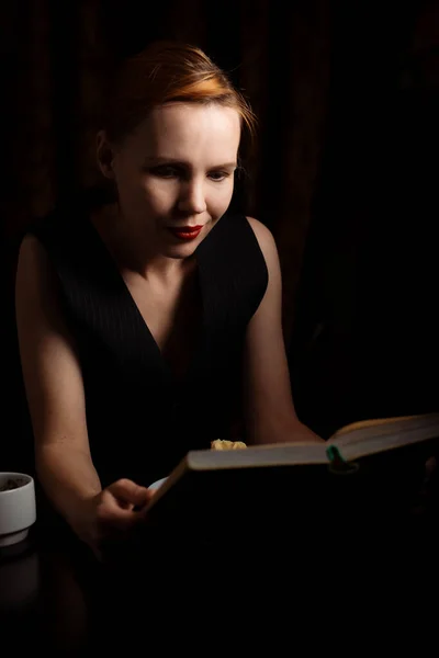 Una Mujer Sienta Una Mesa Con Libro Pastel Oscuridad Una —  Fotos de Stock