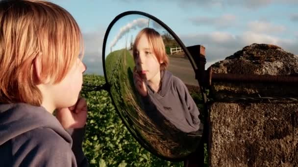 一个九岁至十岁的男孩在镜子里看着自己 — 图库视频影像