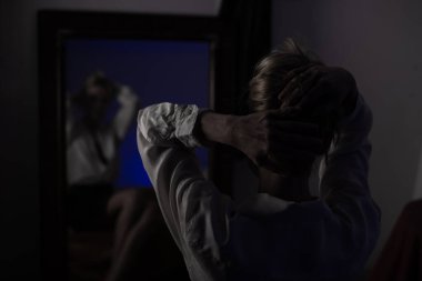 Karanlık bir odada aynanın karşısında yansıyan tanınmayan bir kadın. Siyah ve beyaz resim.