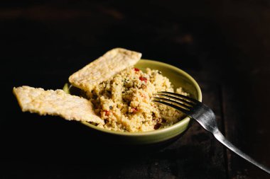 Rice bread and tomato and spice couscous salad on a dark background. Tabbouleh salad.