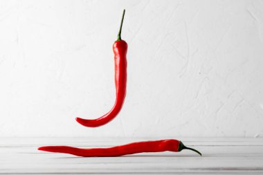 Beyaz ahşap arka planda kırmızı kırmızı kırmızı biber kokusu var. Yiyecek havalanması.