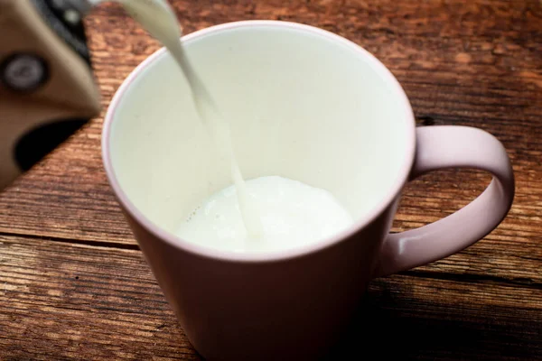 Latte Viene Versato Una Tazza Uno Sfondo Legno Marrone — Foto Stock