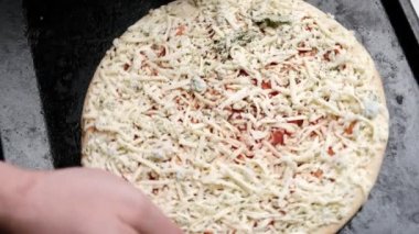 Çiğ pizza bir adamı pişirme kabına koyar. Bol peynirli pizza..