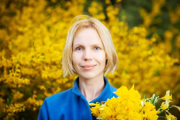 Žena Modrém Kabátě Žlutém Pozadí Květin Drží Ruce Kytici Žlutých — Stock fotografie