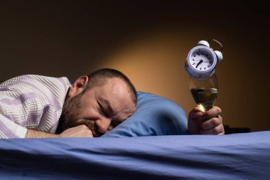 Man and alcoholism. Get drunk with alcohol and oversleep the alarm clock concept. Hangover agony in the morning. Drink alcohol to sleep.