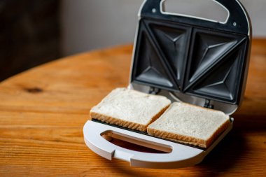 Tahta masada ekmekli tost makinesi. Sandviç hazırlama hazırlığı.