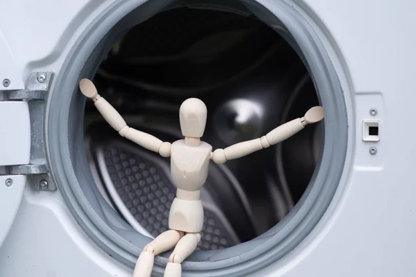 washing machine repair concept. A figurine of a man sits in the open door of a washing machine.