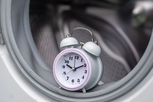 time and washing machine. Waiting, washing duration concept. Open door of washing machine and alarm clock.