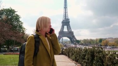 Paris 'te Eyfel Kulesi' nin yakınında bir kadın telefonda konuşuyor. Güneşli bir günde, ceketli orta yaşlı bir kadın. turizm.