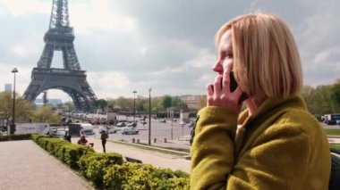 Paris 'te Eyfel Kulesi' nin yakınında bir kadın telefonda konuşuyor. Güneşli bir günde, ceketli orta yaşlı bir kadın. turizm.