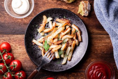 Ketçaplı kızarmış patates, mayonez ve ahşap arka planda otlar..