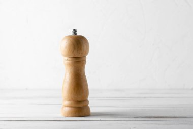 Beyaz ahşap arka planda ahşap biber öğütücü.