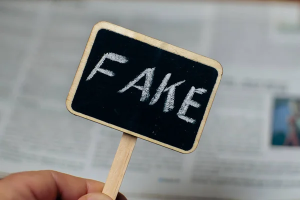 Fake news. Sign with the inscription fake on the background of newspapers.