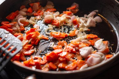 Soğan ve havuç tavada kızartılır. Koyu arkaplan.