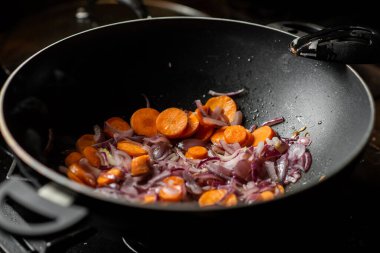 Soğan ve havuç kızartma tavasında kızartılır. Yemek hazırlığı.