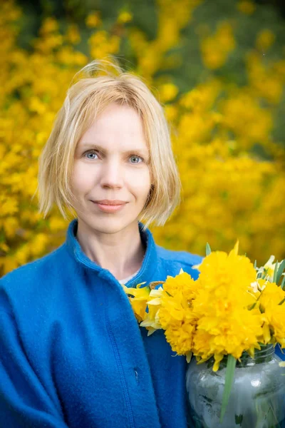 Žena Modrém Kabátě Žlutém Pozadí Květin Drží Ruce Kytici Žlutých — Stock fotografie