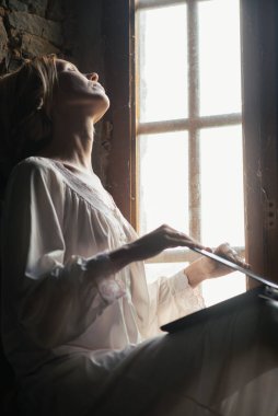 Bir kadın pencerenin yanındaki bilgisayarı kapatıyor. Mesai bitti. Serbest Çalışan, Evden Çalışan.