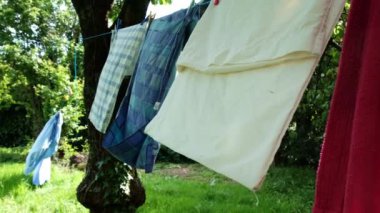 Yatak çarşafları iple kurutulur. Güneşli bir gün, yeşil çayır kırsal.