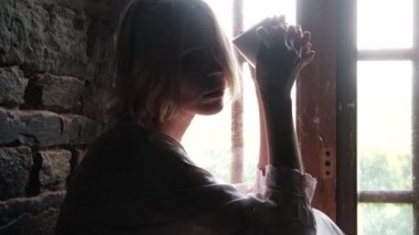 Düşünceli bir kadın pencerenin yanında kahve içiyor..