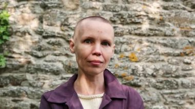 Taş duvar arkasında orta yaşlı kel bir kadın portresi. Özgürlük, zafer, kemoterapi konsepti.