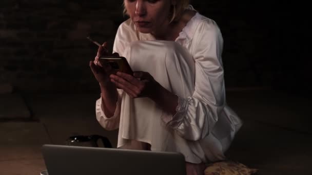 Женщина Курит Сидит Телефоном Перед Ноутбуком Темной Комнате — стоковое видео