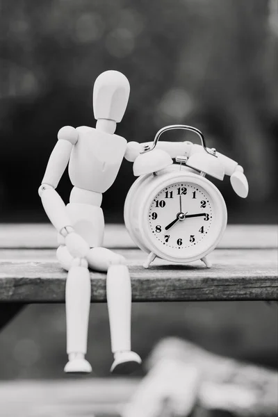Figure of a man and an alarm clock. The concept of time, circadian rhythm, deadline. Black and white image, vertical orientation.