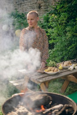 Bir kadın ızgara için sebze hazırlar, güneşli bir günde açık havada kuşkonmaz keser. Vejetaryen yeşil ızgara.