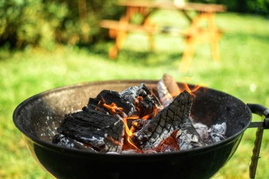Yeşil yaprakların arka planında ızgarada odun yakmak. Izgarayı yemek için hazırlıyorum..