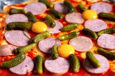 Salatalık turşulu pizza. Ev yapımı pizza pişirmek. Domates sosuyla kaplı hamurun üzerine sosis ve salatalık turşusu serdim..