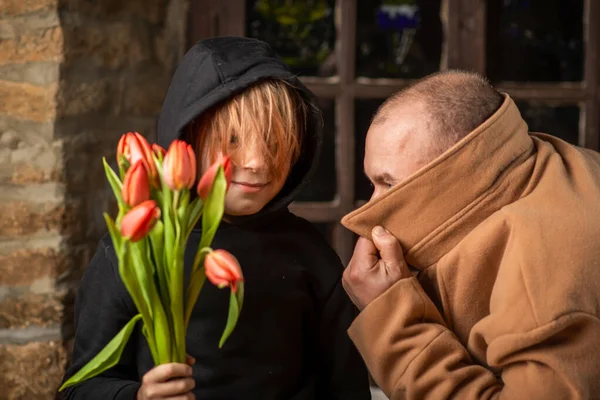 一个小男孩拿着一束花 紧挨着一个蒙着脸的男人 准备出其不意的阴谋者 — 图库照片