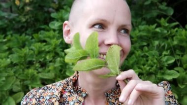 Elinde nane yaprağı tutan mutlu, kel bir kadın. ruh sağlığı.