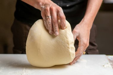 Yemek hamuru. Kadınların elleri mutfakta hamur yoğuruyor. Tanınmayan kadın yemek pişirmekle meşgul..