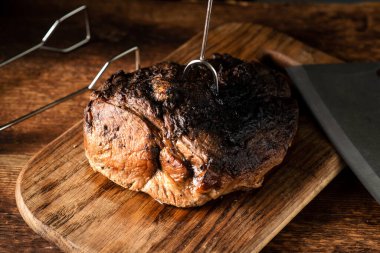 Bir parça pişmiş et. Ahşap bir tahtanın üzerinde fırında pişirilmiş baharatlı domuz eti..