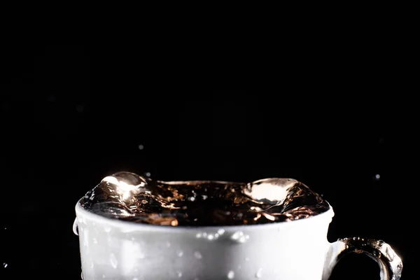 黒い背景にカップの表面の水の波 — ストック写真