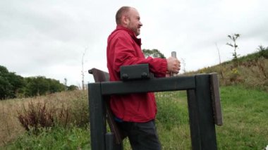 Orta yaşlı bir adam parkta simülatörde çalışıyor. Basın için alıştırmalar yapıyor.