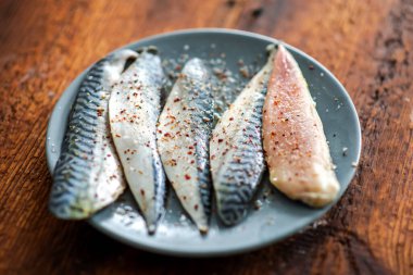 Çiğ balık filetosu, ahşap bir zemindeki bir tabağa tuz ve baharat serpiştirilmiş. Uskumru filetosu..