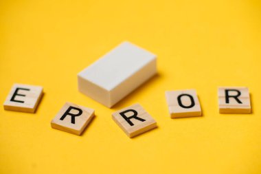 Harflerden oluşan bir kelime - sarı arkaplandaki hata ve silgi.