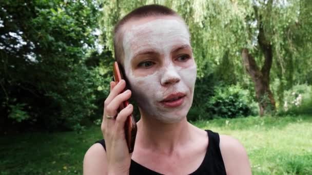 Žena Bílou Kosmetickou Maskou Obličeji Mluví Mobilním Telefonu Pozadí Zeleného — Stock video