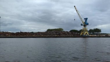 Çöp tenekesi ve hurda metal taşıyan bir vinçle endüstriyel liman manzarası