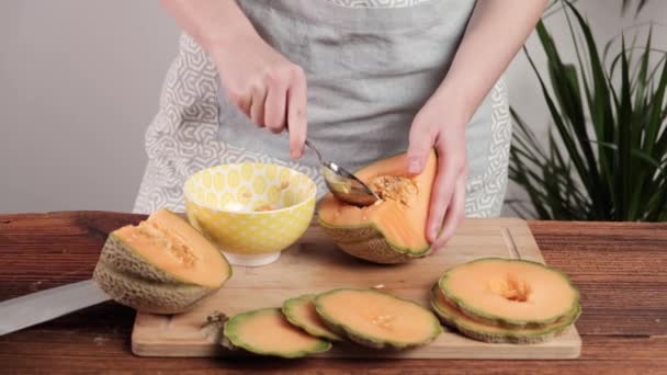 女人的手从种子上清洁甜瓜 厨房背景 — 图库视频影像